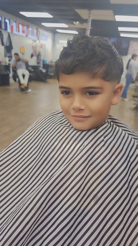 A young client's finished haircut, smiling, in the shop.